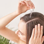 A woman using a scalp serum dropper to stimulate hair growth