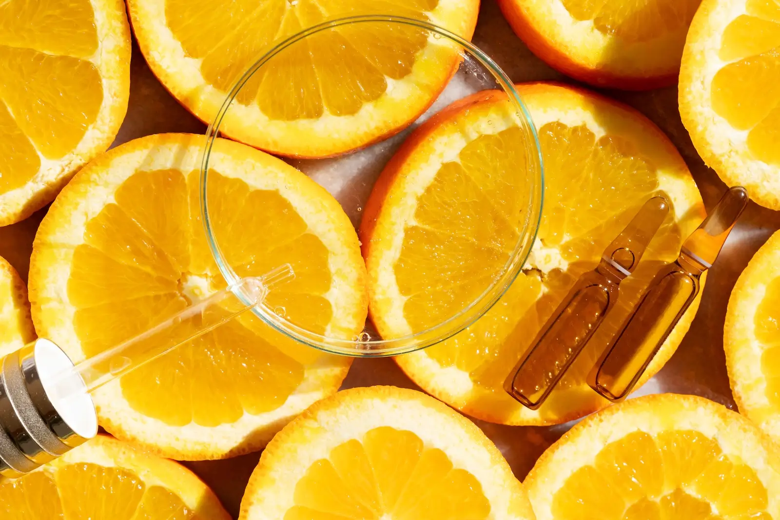 glass petri dish on top of citrus slices with vitamin c serum, anti-oxidant to protect against free radicals and prevent signs of aging